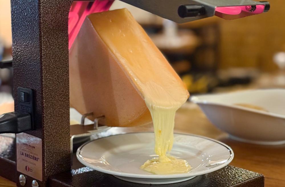 fromage &agrave; raclette fondu coulant dans une assiette avec appareil traditionnel