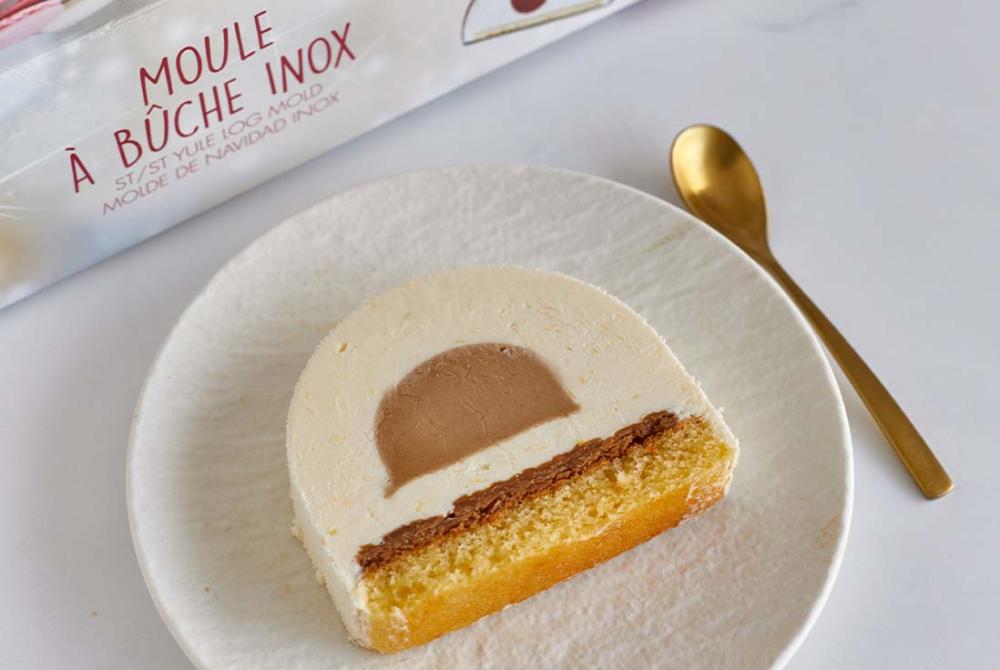 Image d'une part de buche de noel citron et noisette posées dans une assiette, à côté du kit moule à buche en U de GOBEL.