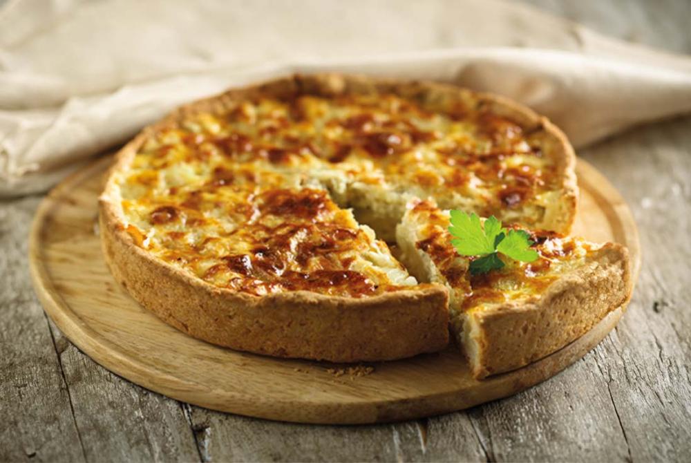 Gros plan sur une part de tarte à l’oignon mettant en valeur les filaments d’oignons dorés et la texture fondante.