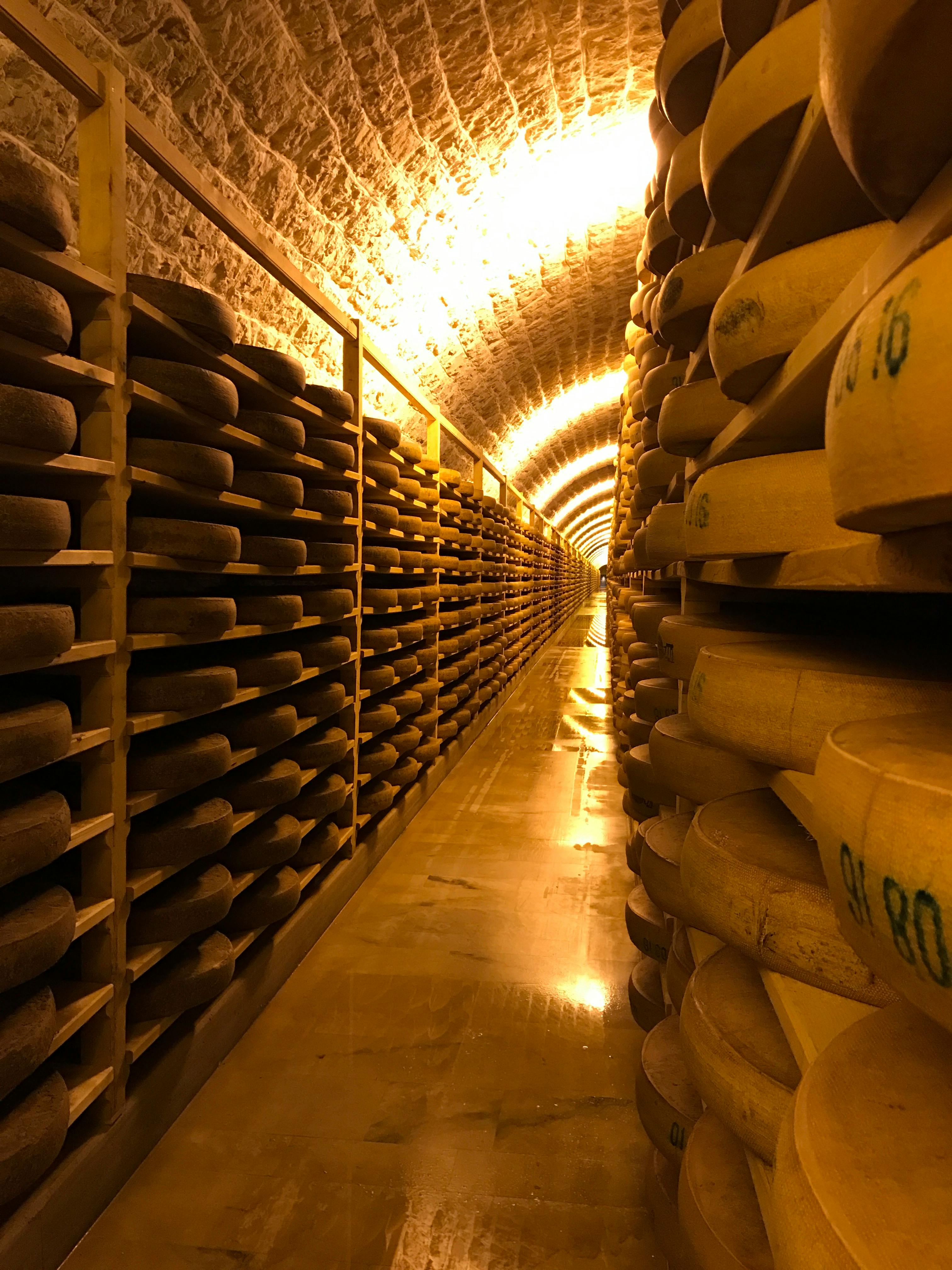 Photos de plusieurs meules de fromage posées sur des étagères en bois